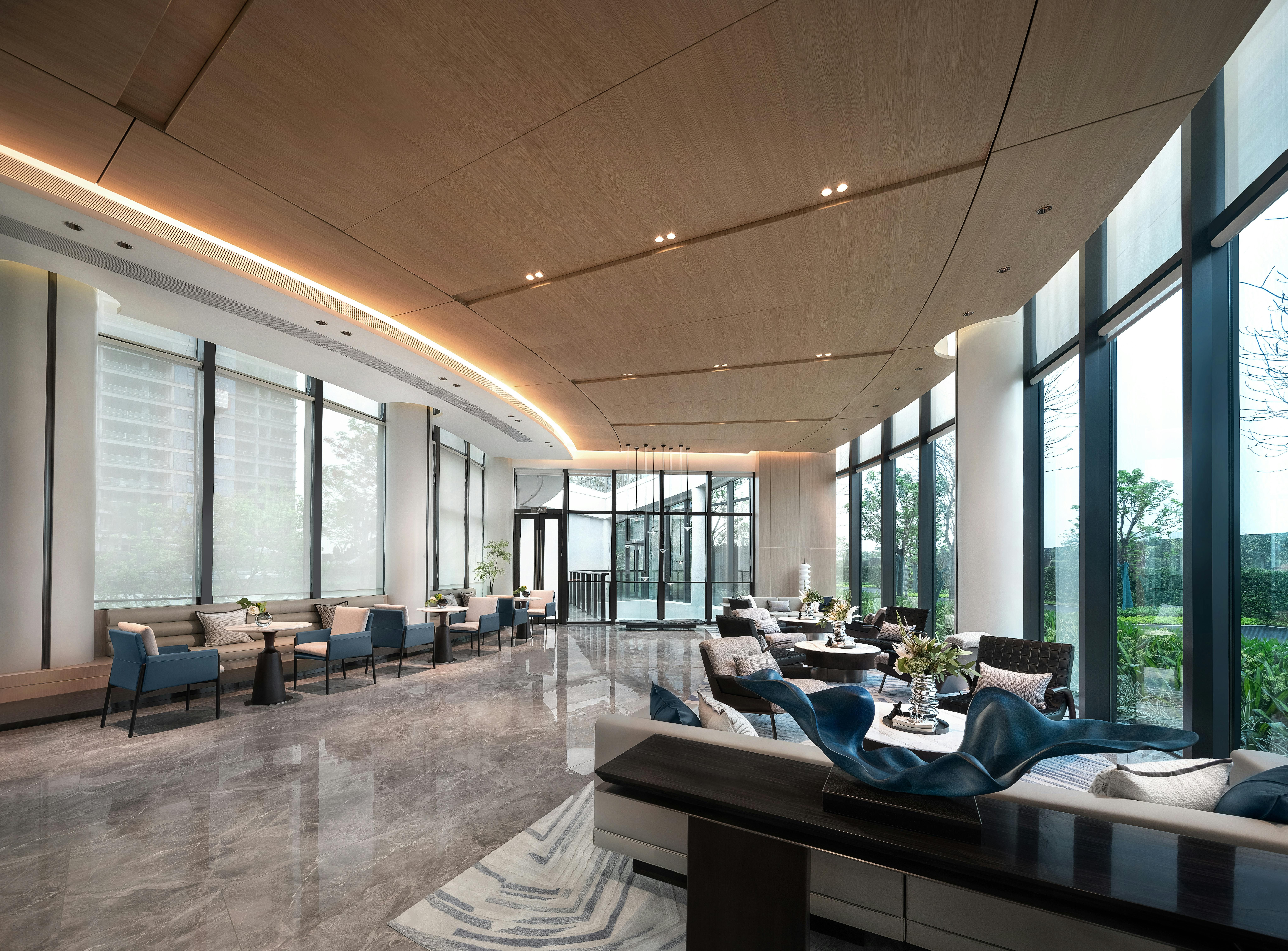 Elegant high-end lobby with marble floors, tall glass windows, and lounge seating.