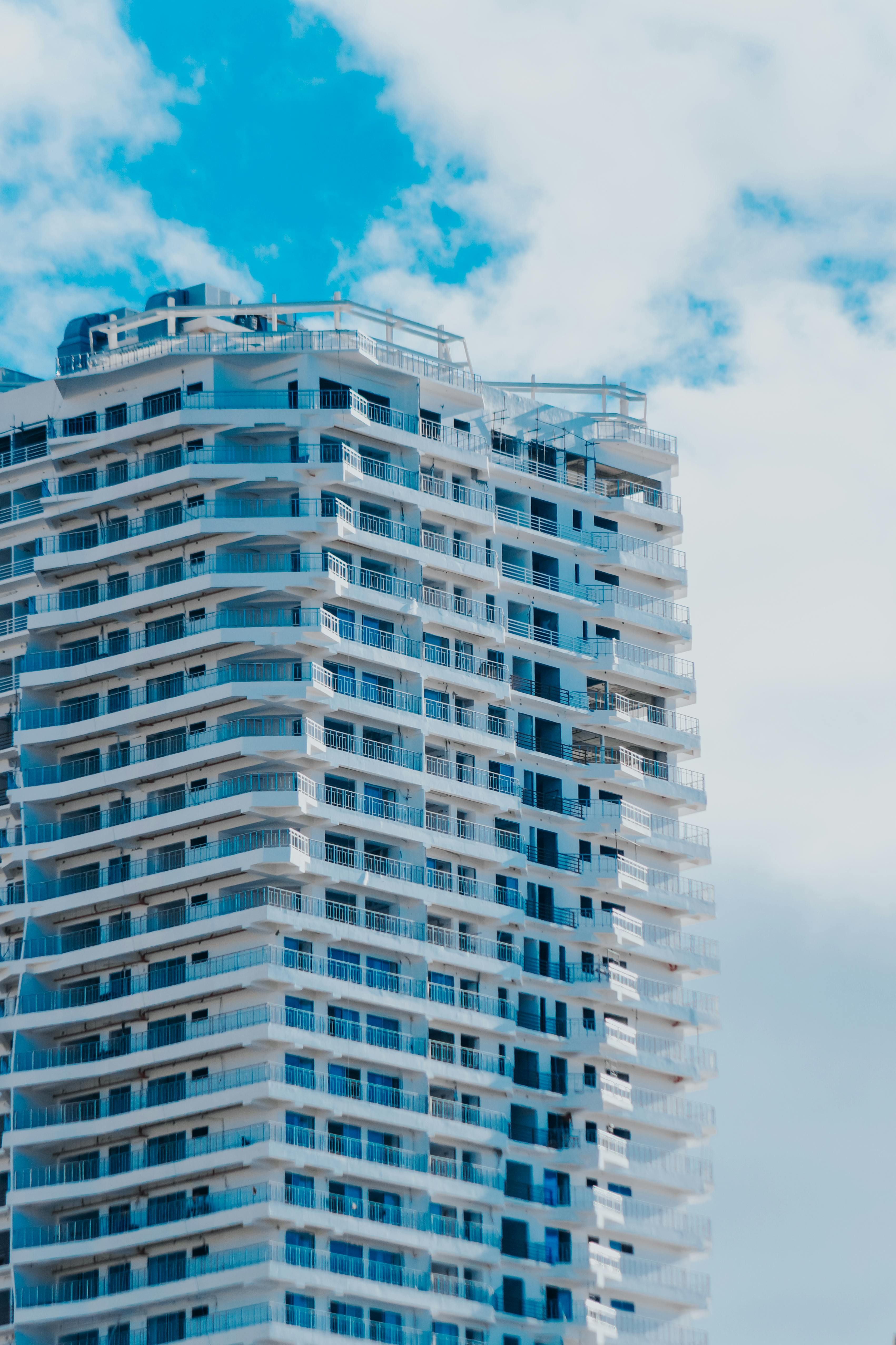 Luxury residential tower with white balconies under a blue sky.